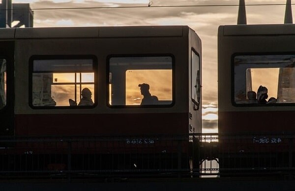 Menschen sitzen im Zugwaggon vor einem Sonnenuntergang